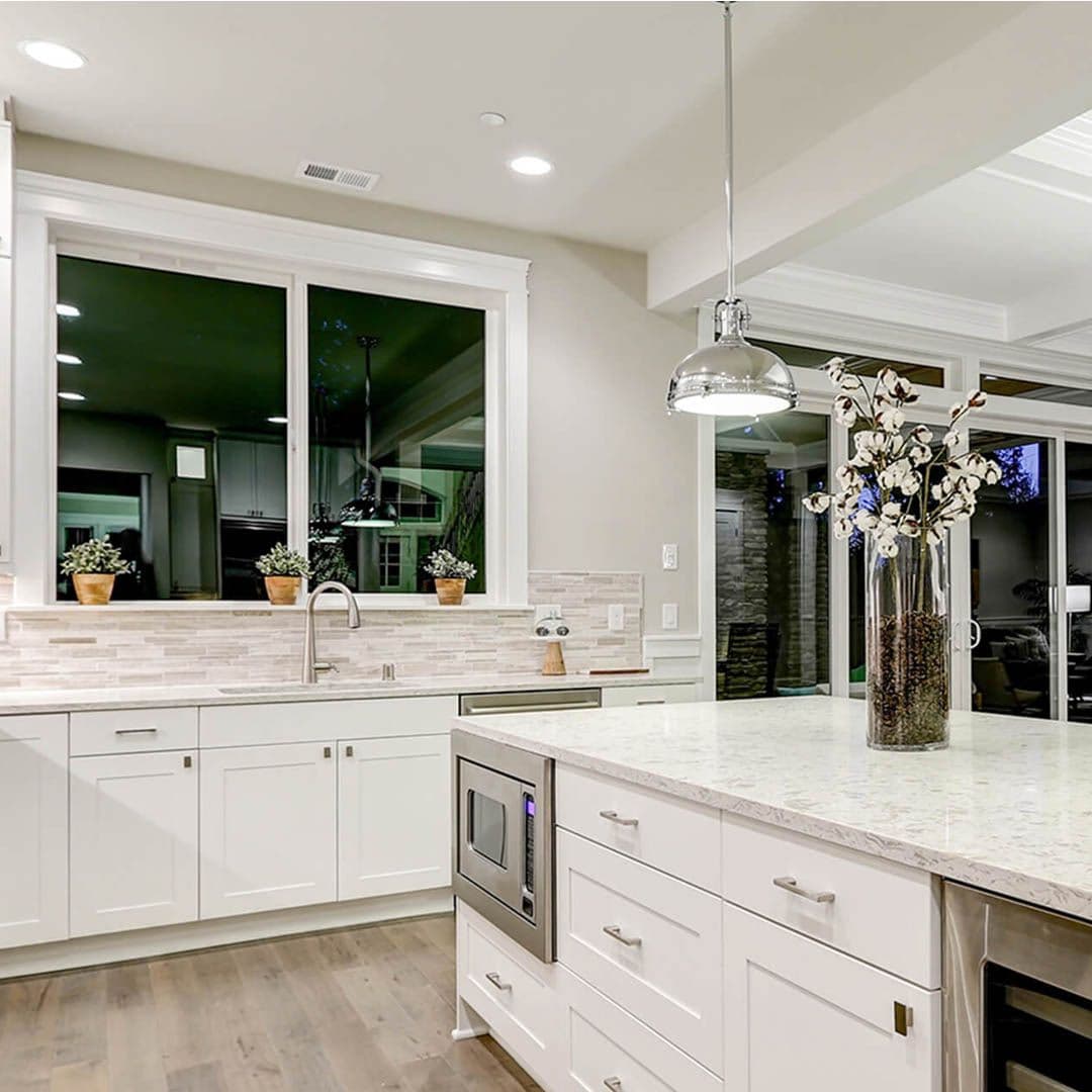 Large sliding windows in an all-white kitchen. Glass sliding doors are also visible in the background.