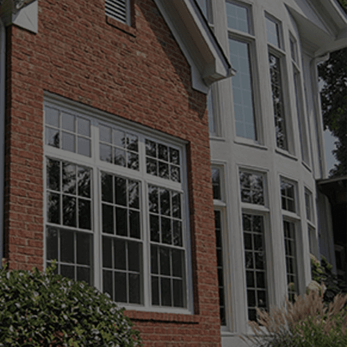 A red brick house with double-hung windows and two-story bow windows.