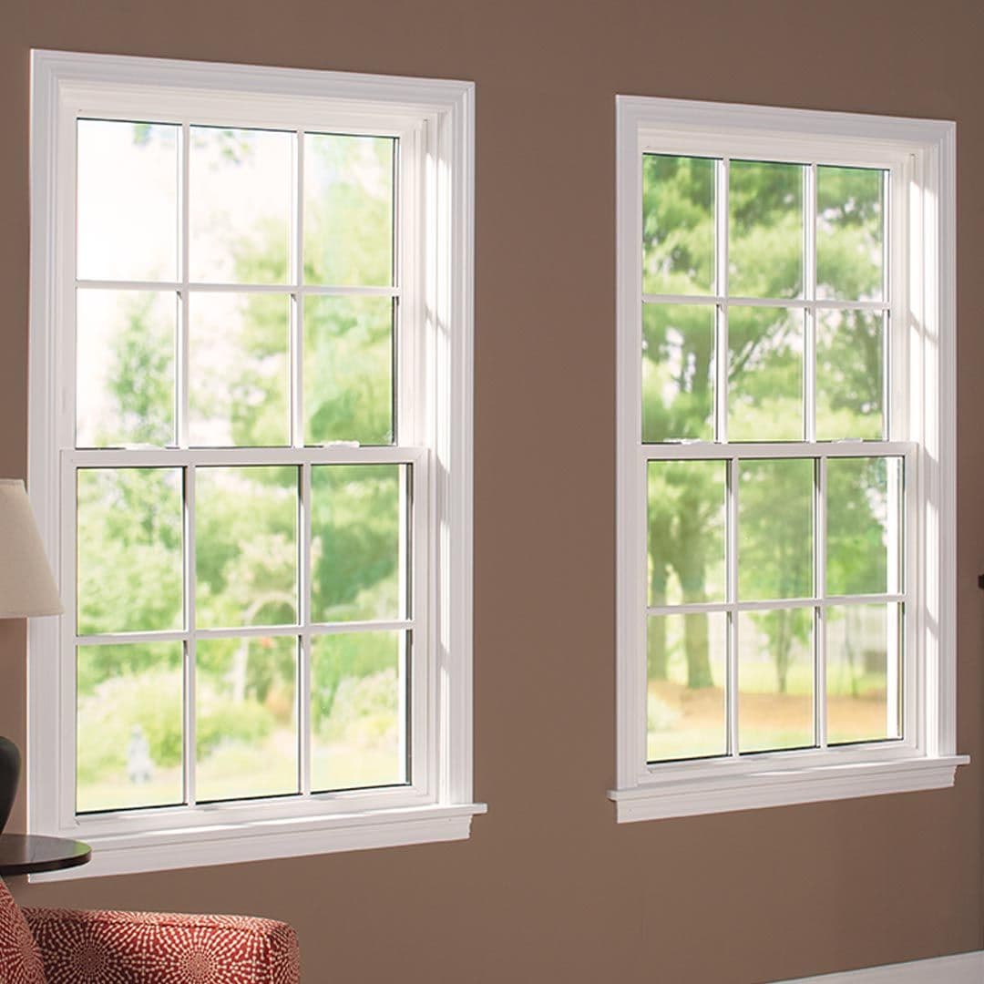 Two double-hung windows with latices and white trim in a beige room.
