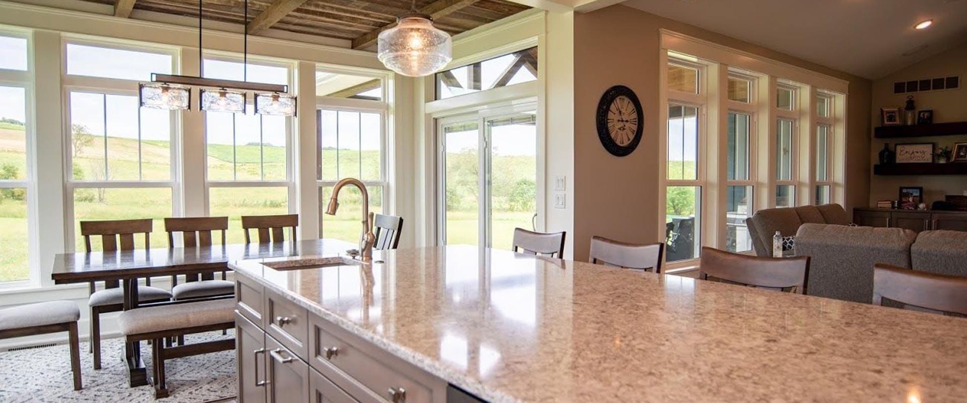 A kitchen with an island and dining area with multiple double-hung windows and sliding glass doors.
